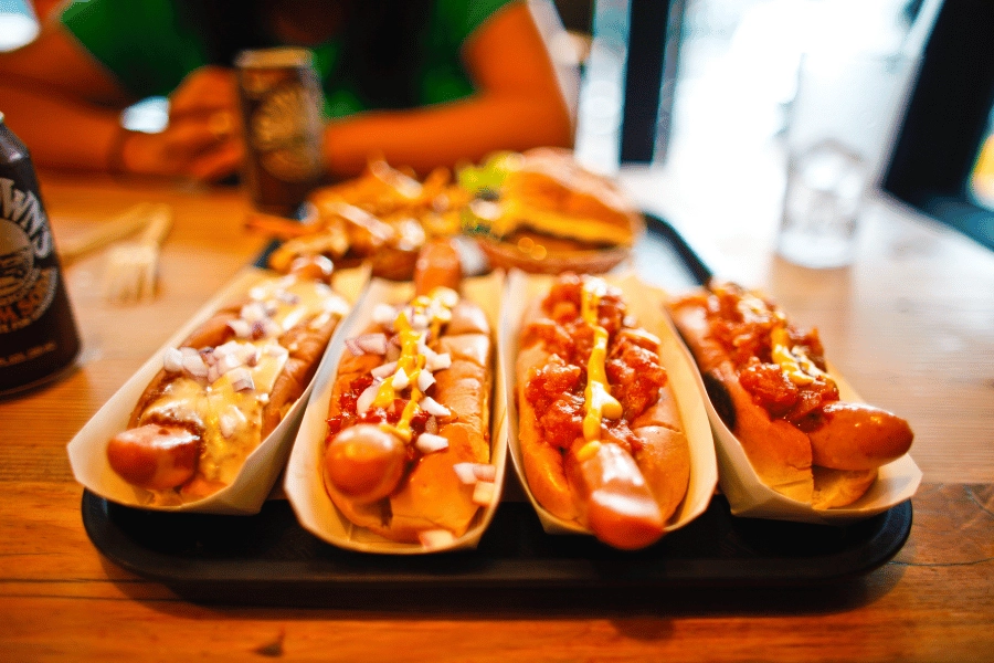 four long hot dogs served with chili, onion, and other toppings